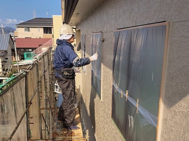 二階の外壁に上塗りしている様子